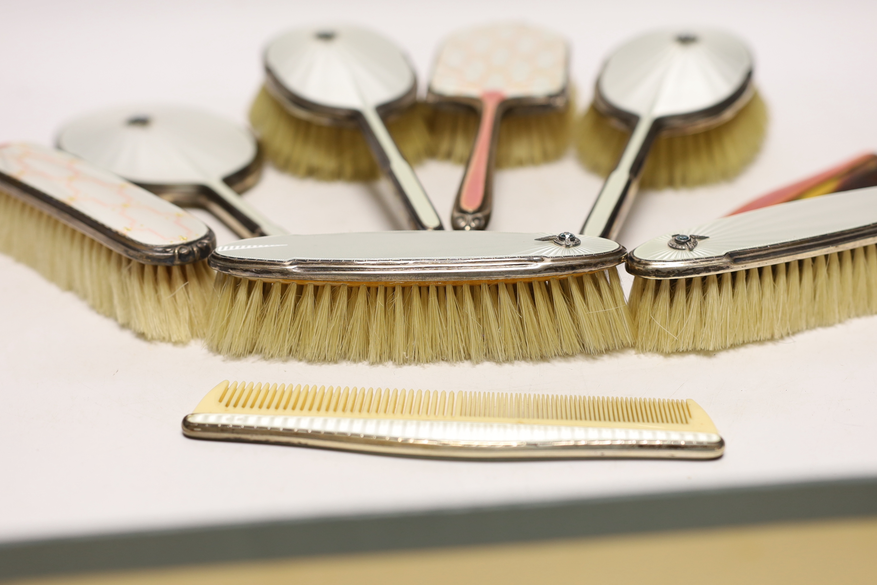 A George VI Art Deco silver, guilloche enamel, blue zircon and marcasite set five piece mirror and brush set and similar enamelled comb, Albert Carter, Birmingham, 1936/7, together with three other later silver and ename